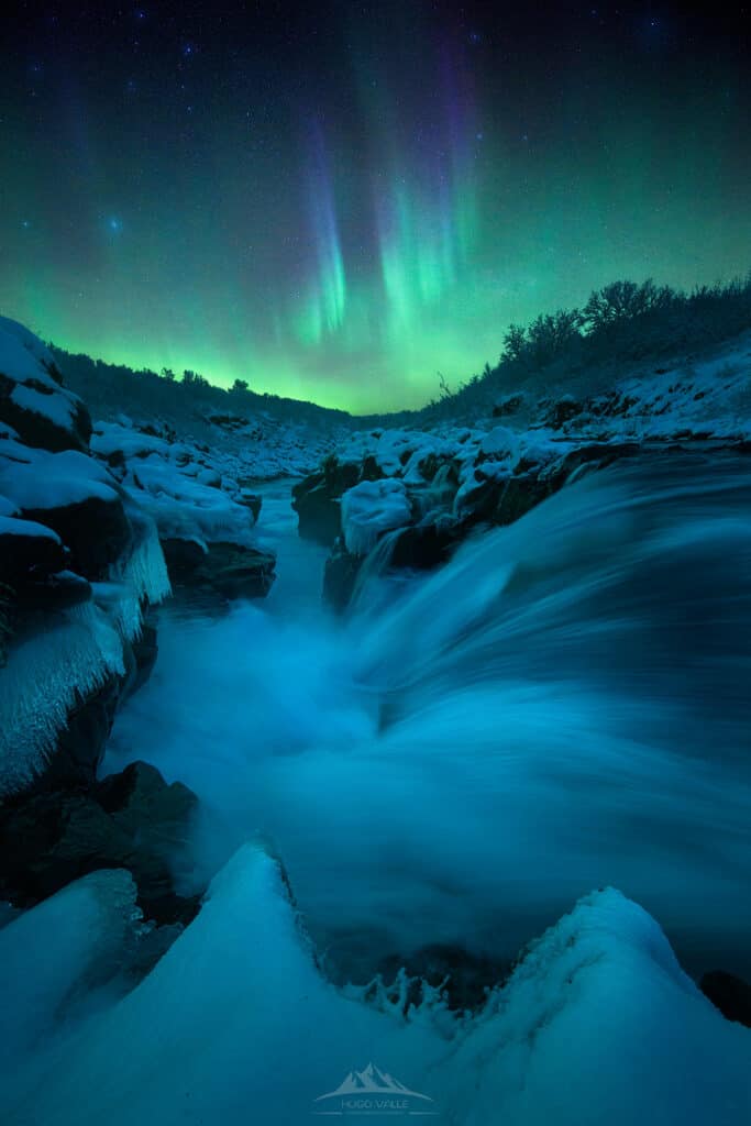 Fotografía nocturna de auroras boreales sobre una cueva de hielo en Islandia.