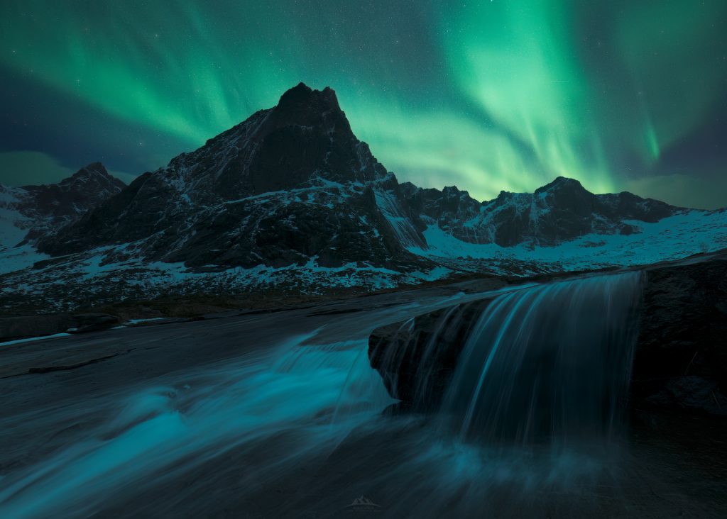 Gran aurora boreal verde sobre el paisaje nevado y cabañas rojas en las Islas Lofoten.