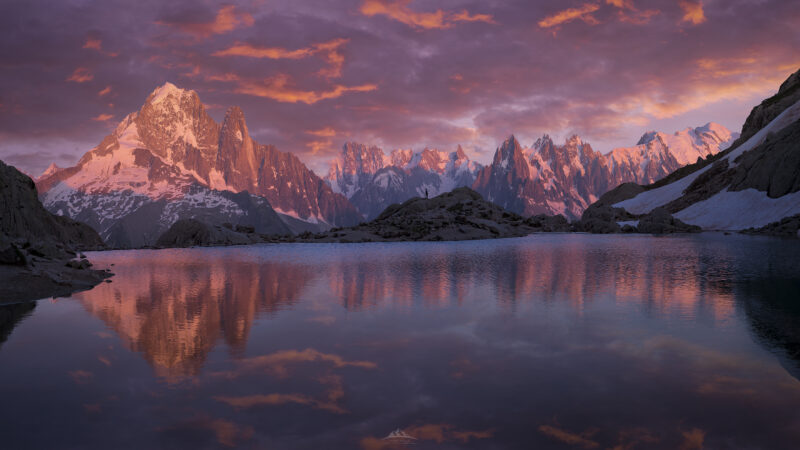 Fotografía de paisaje del alpenglow al atardecer sobre el macizo del Mont-Blanc y las agujas de Chamonix reflejados en las aguas del Lac Blanc en los Alpes Franceses.